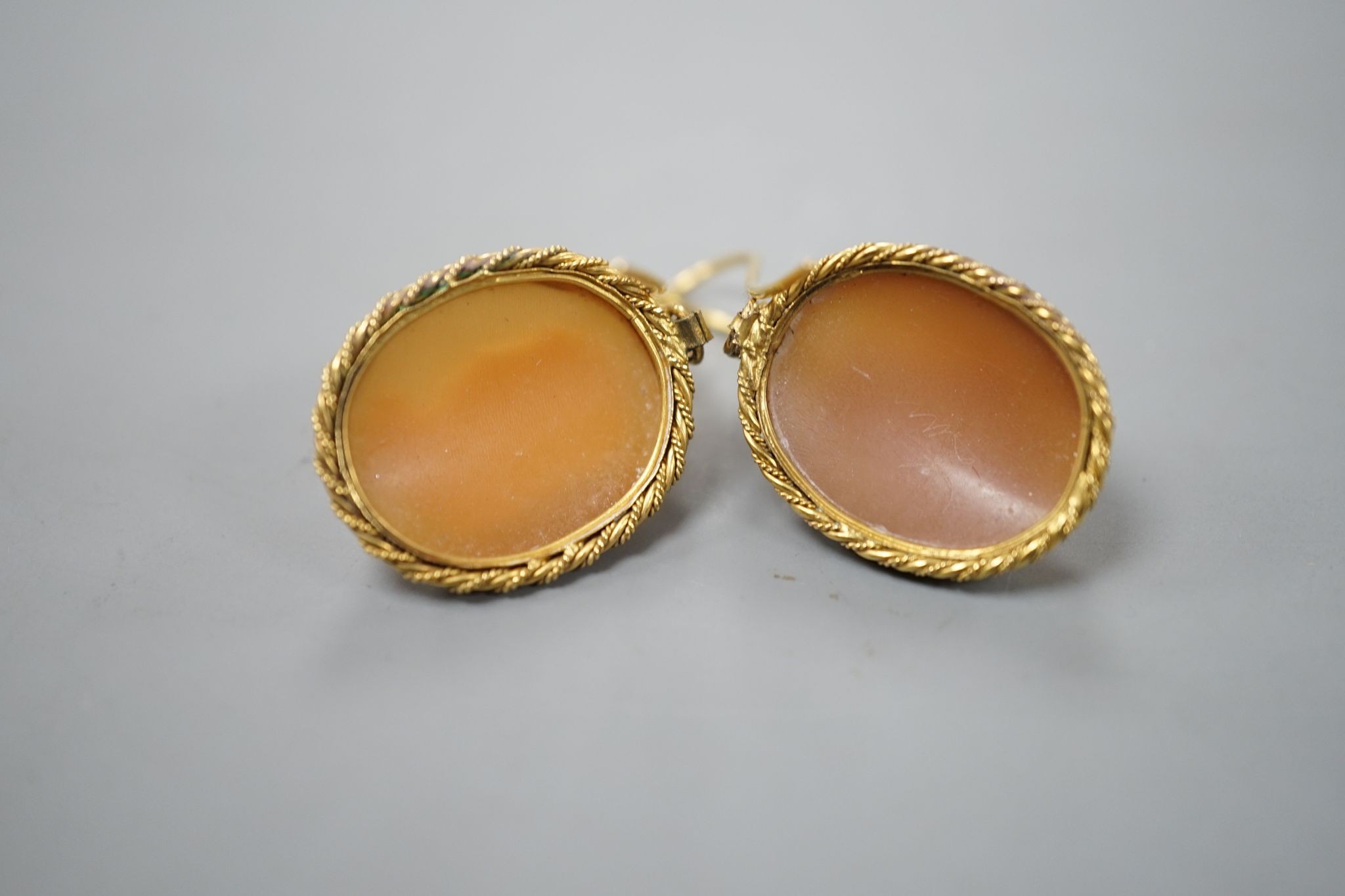 A pair of early 20th century yellow metal and oval cameo shell earrings, carved with a lady to sinister and a gentleman to dexter, overall 40mm, gross 6.2 grams.